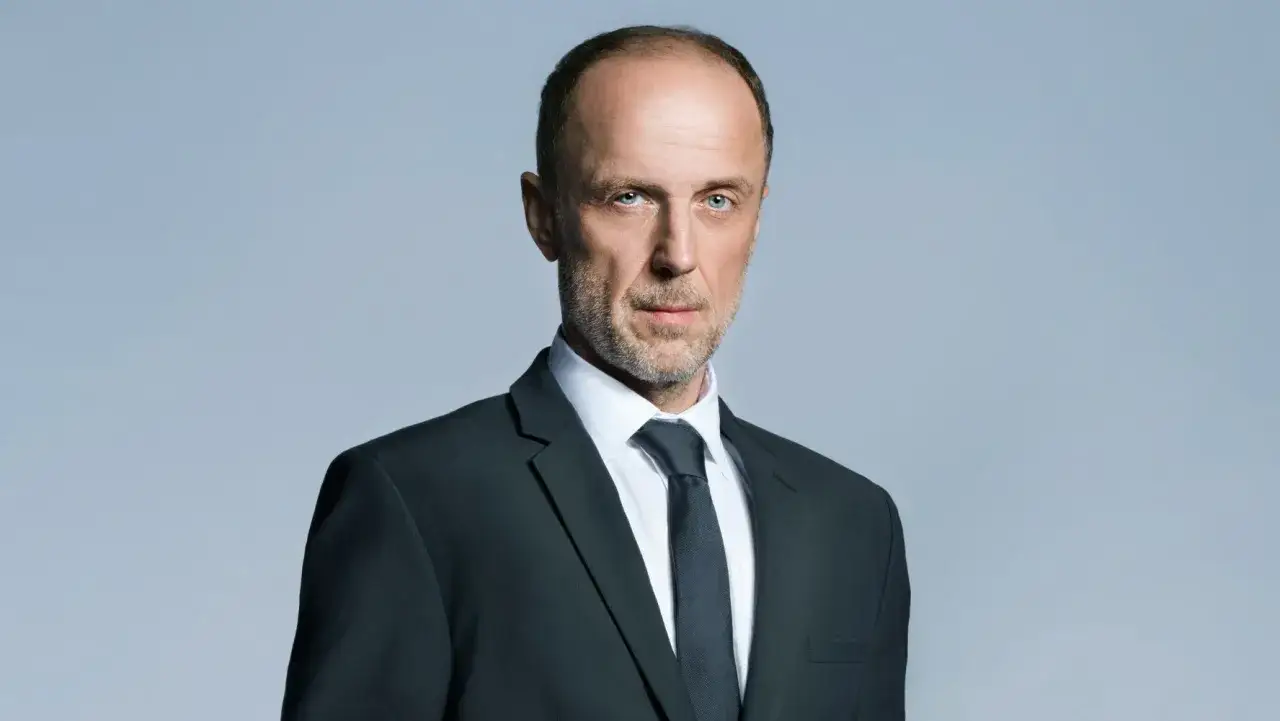 Łukasz Simlat w garniturze, gotowy do roli w kolejnych filmach.