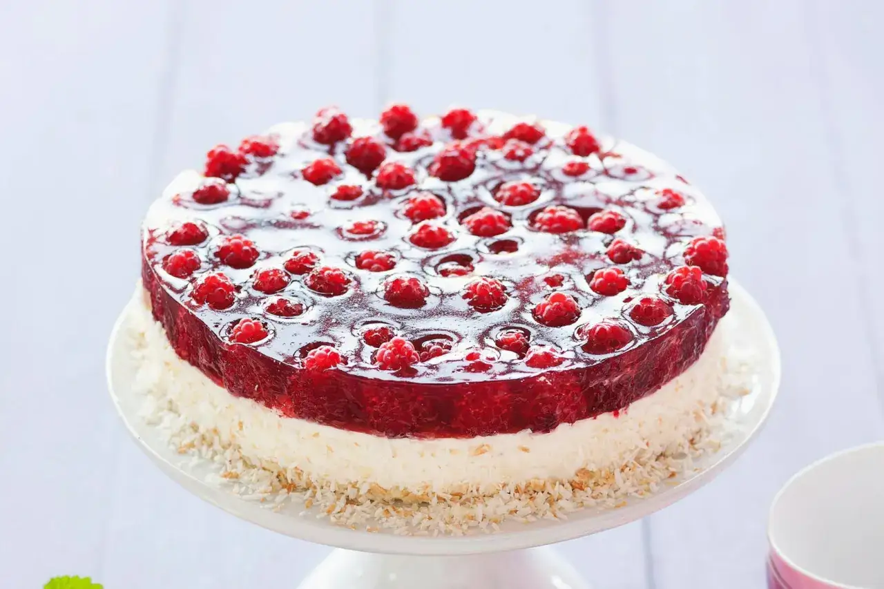Kokos-Himbeer-Torte mit frischen Himbeeren in Gelee auf Kokosboden, ein Genuss für Augen und Gaumen.
