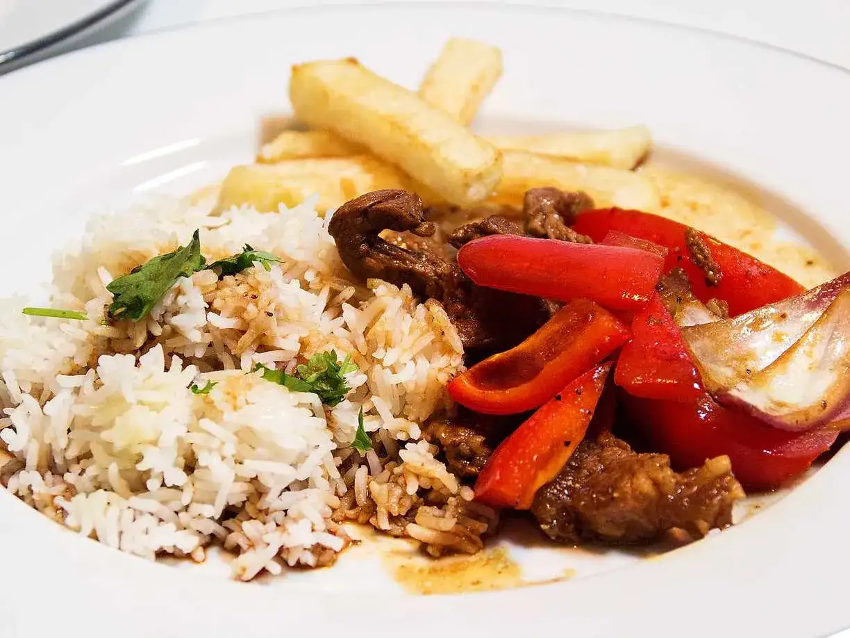 En portion lomo saltado med ris, pommes frites, möra biffstrimlor, paprika och lök.