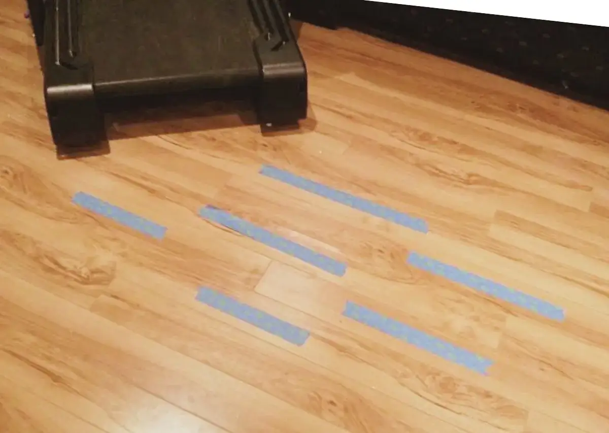 Marcando con cinta azul las &aacute;reas a reparar en el suelo laminado.