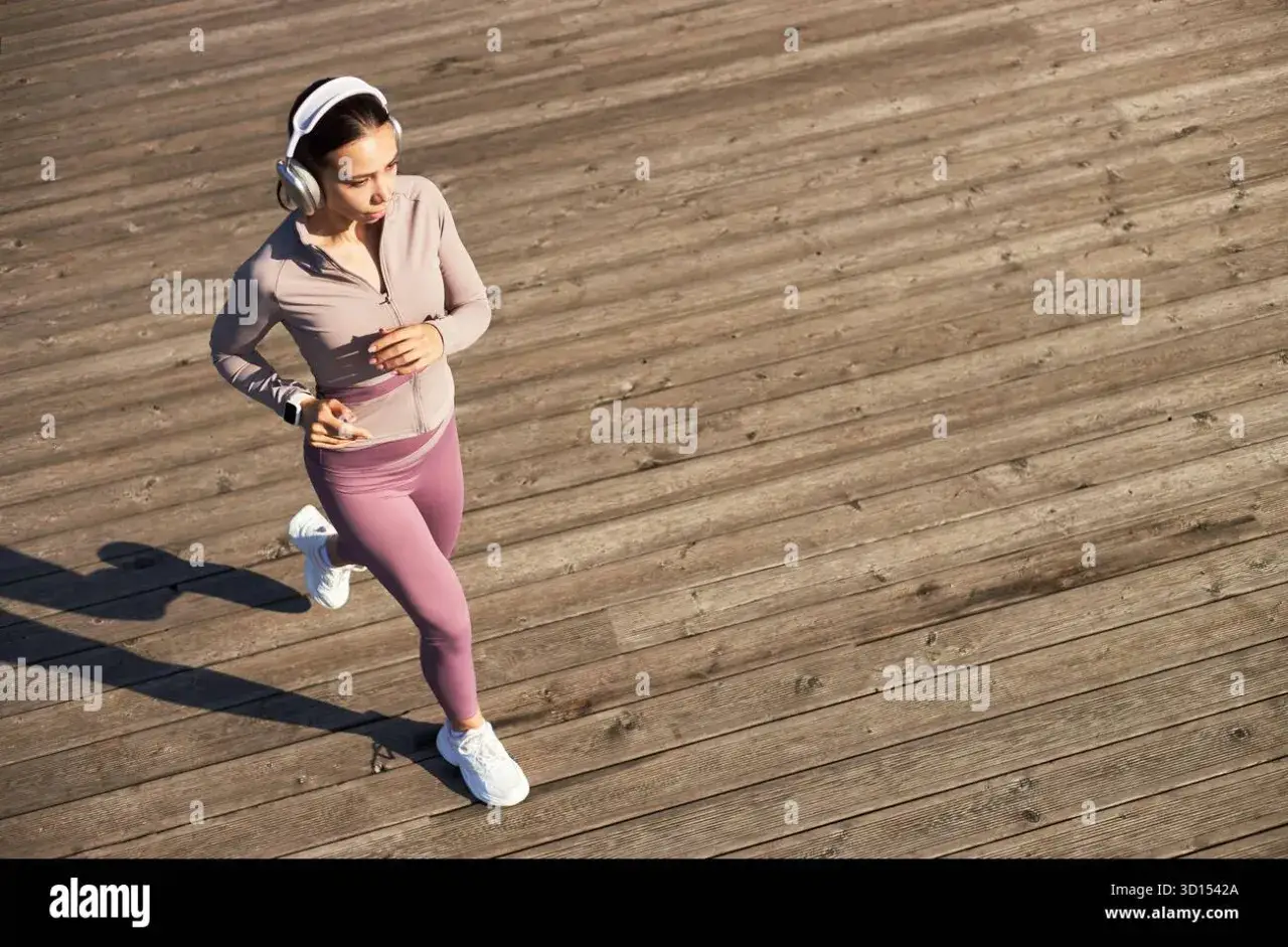 Junge Frau mit Kopfhörern joggt auf Holzplanken, die perfekte Musik zum Joggen im Ohr.