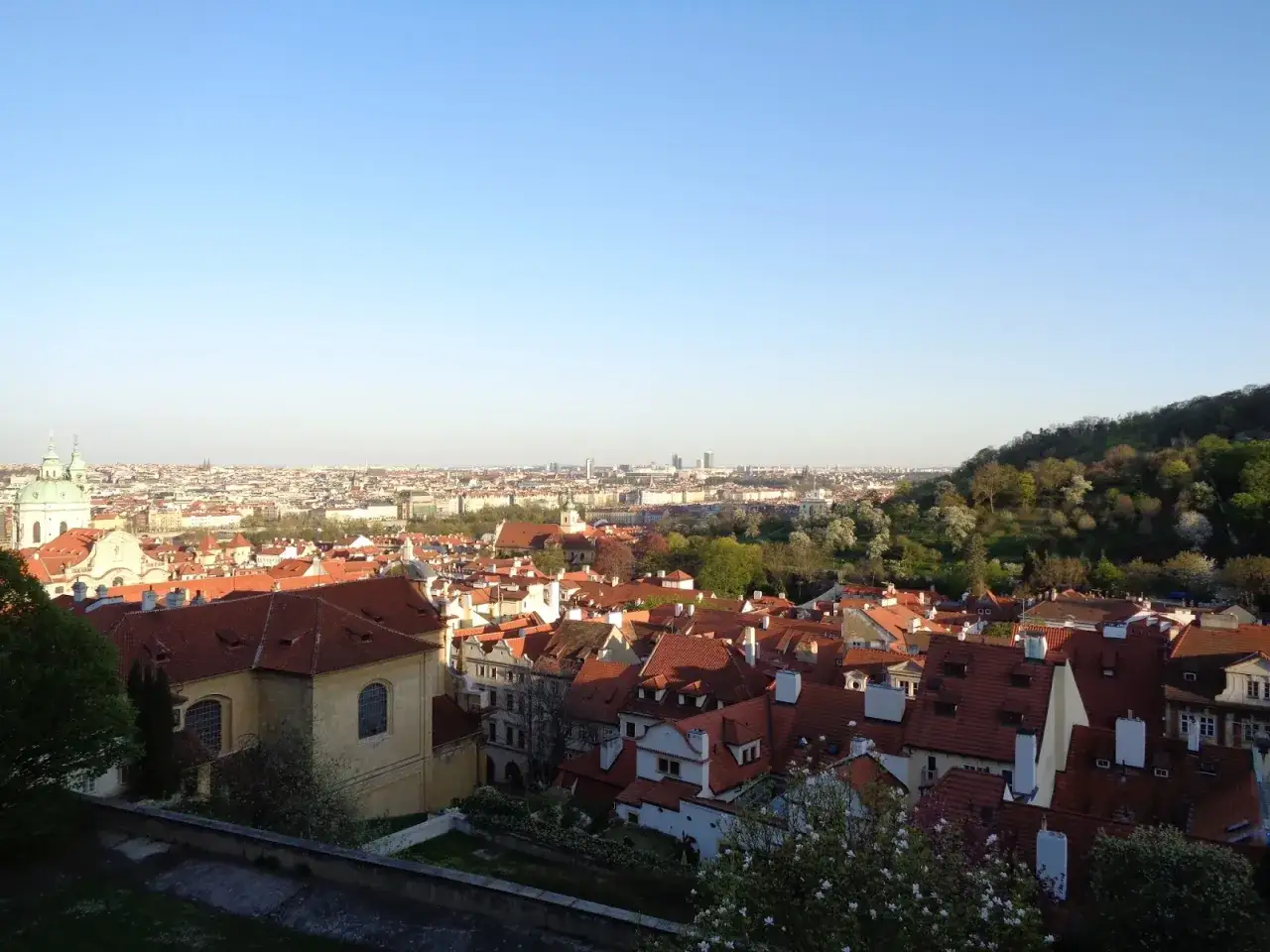 Widok na dachy Pragi z górującym nad nimi **zamkiem na Hradczanach**.