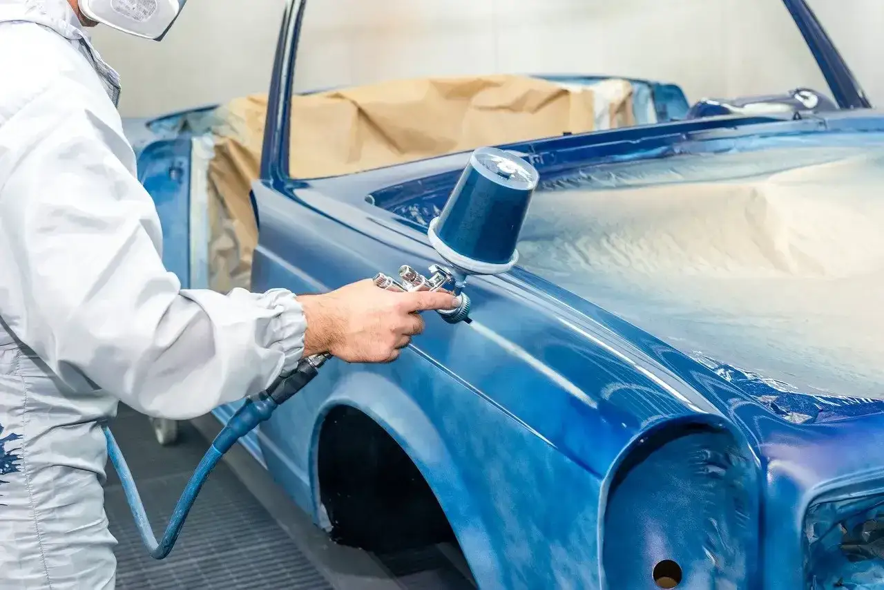 Peinture d'une voiture bleue par un professionnel. Le prix de la carrosserie est justifi&eacute; par ce travail minutieux.