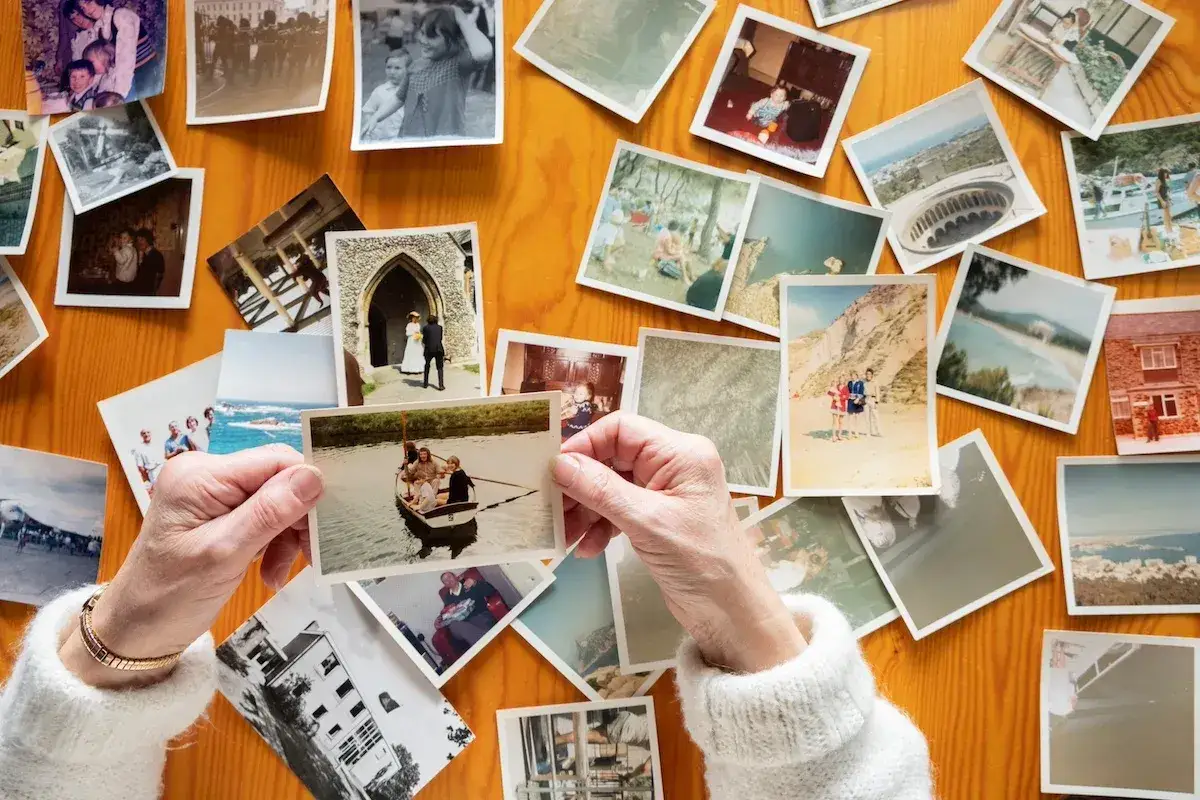 Mani anziane sfogliano vecchie foto stampate su un tavolo di legno, un modo per conservare le foto stampate e i ricordi.