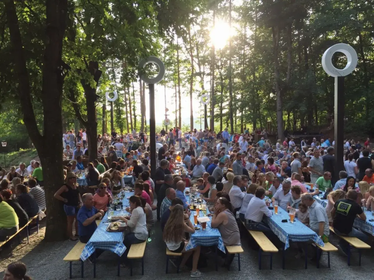 Viele Menschen genie&szlig;en das Leben in einem sonnigen cbc biergarten unter B&auml;umen.