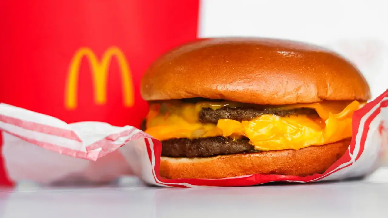 McDouble z dwoma kotletami i serem, w tle czerwone logo McDonald's. Zastanawiasz się nad mcdouble kcal?