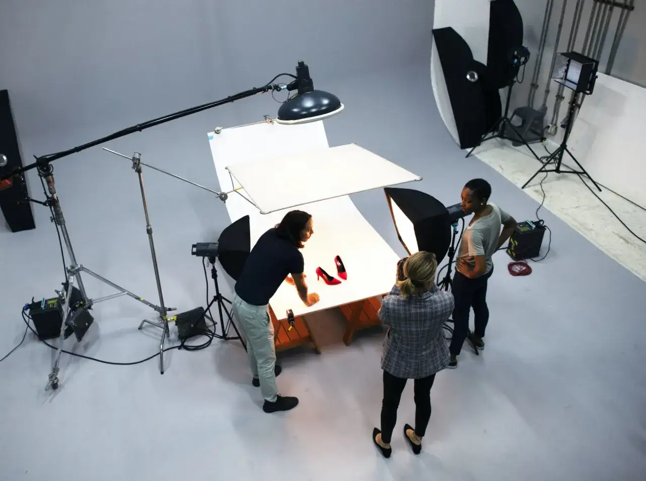 Une équipe réalise une **photographie de produits** de chaussures rouges dans un studio.