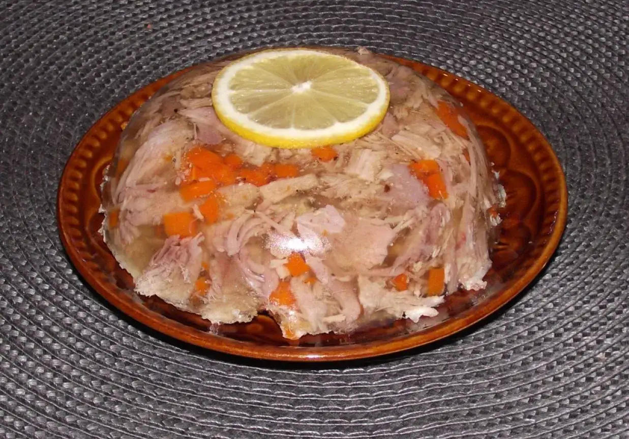 Galareta wieprzowa z marchewką, gdzie jest golonka u świni? Na talerzu, ozdobiona plasterkiem cytryny.