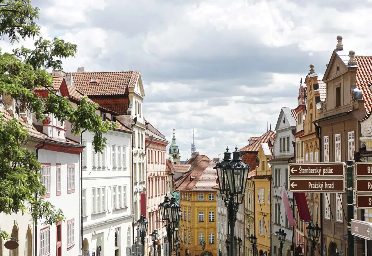 Urokliwa ulica w praga stare miasto, z kolorowymi kamienicami, zabytkowymi latarniami i drogowskazami.