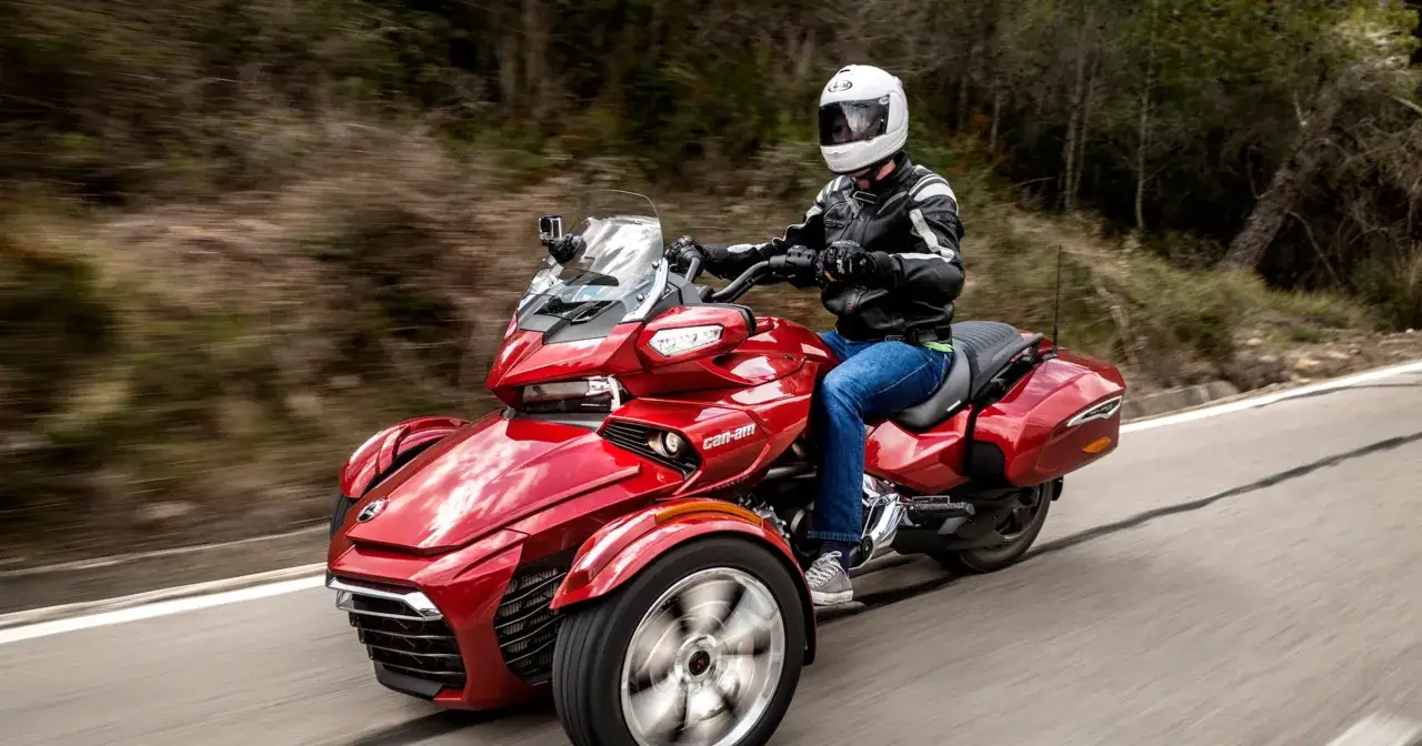 Czerwony trójkołowiec Can-Am jedzie po krętej drodze. W Polsce do jakiej pojemności można jeździć motorem bez prawa jazdy?