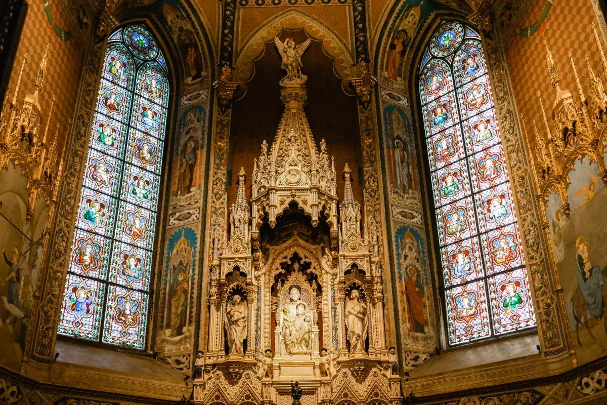 Prunkvoller Altar mit Buntglasfenstern in einer Kirche in Loreto, Italien. Engel und Heilige zieren die Wände und das kunstvolle Retabel.