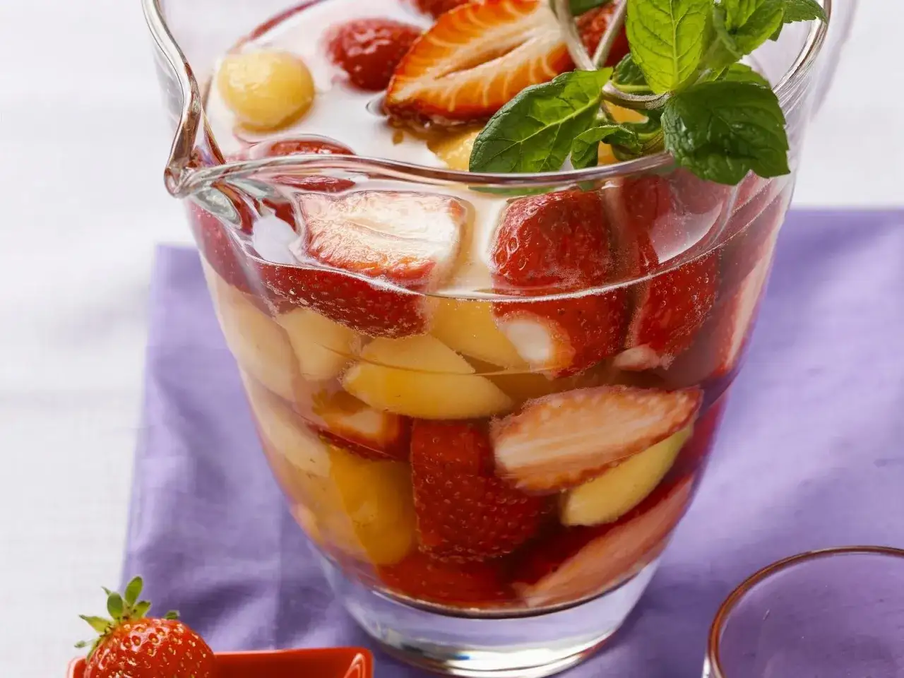 Erfrischende melonenbowle ohne alkohol, gefüllt mit Erdbeeren, Melonenbällchen und Pfirsichstücken, garniert mit Minze.