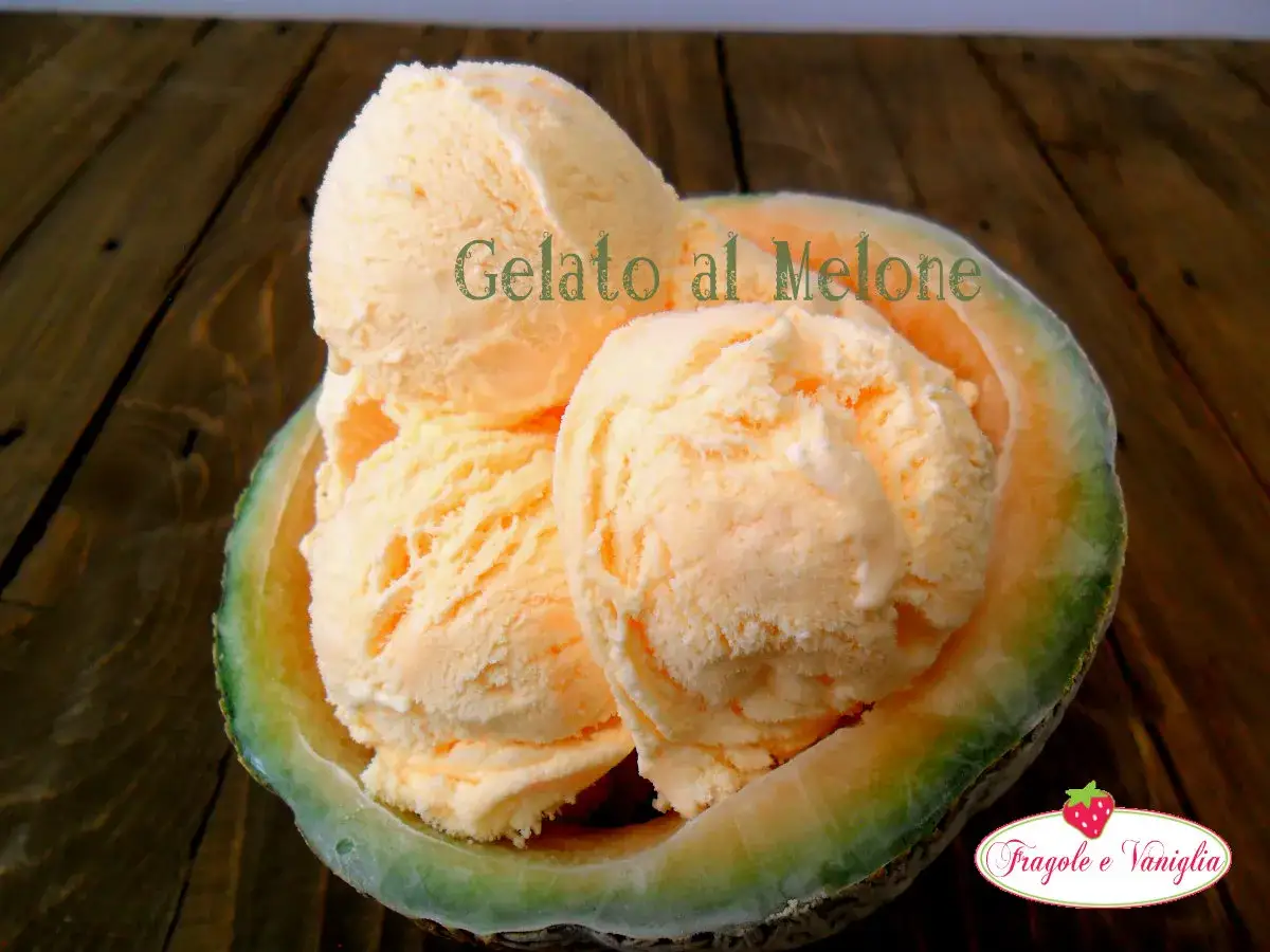 Coppa di gelato al melone servita in una ciotola di melone, su un tavolo di legno.