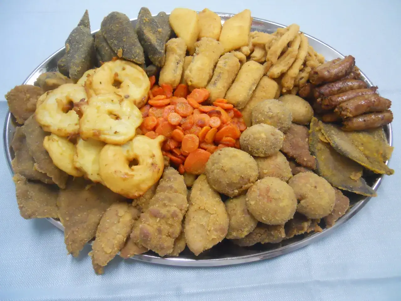 Vassoio con vari piatti tipici torinesi: frittelle, verdure, polpette e salumi.