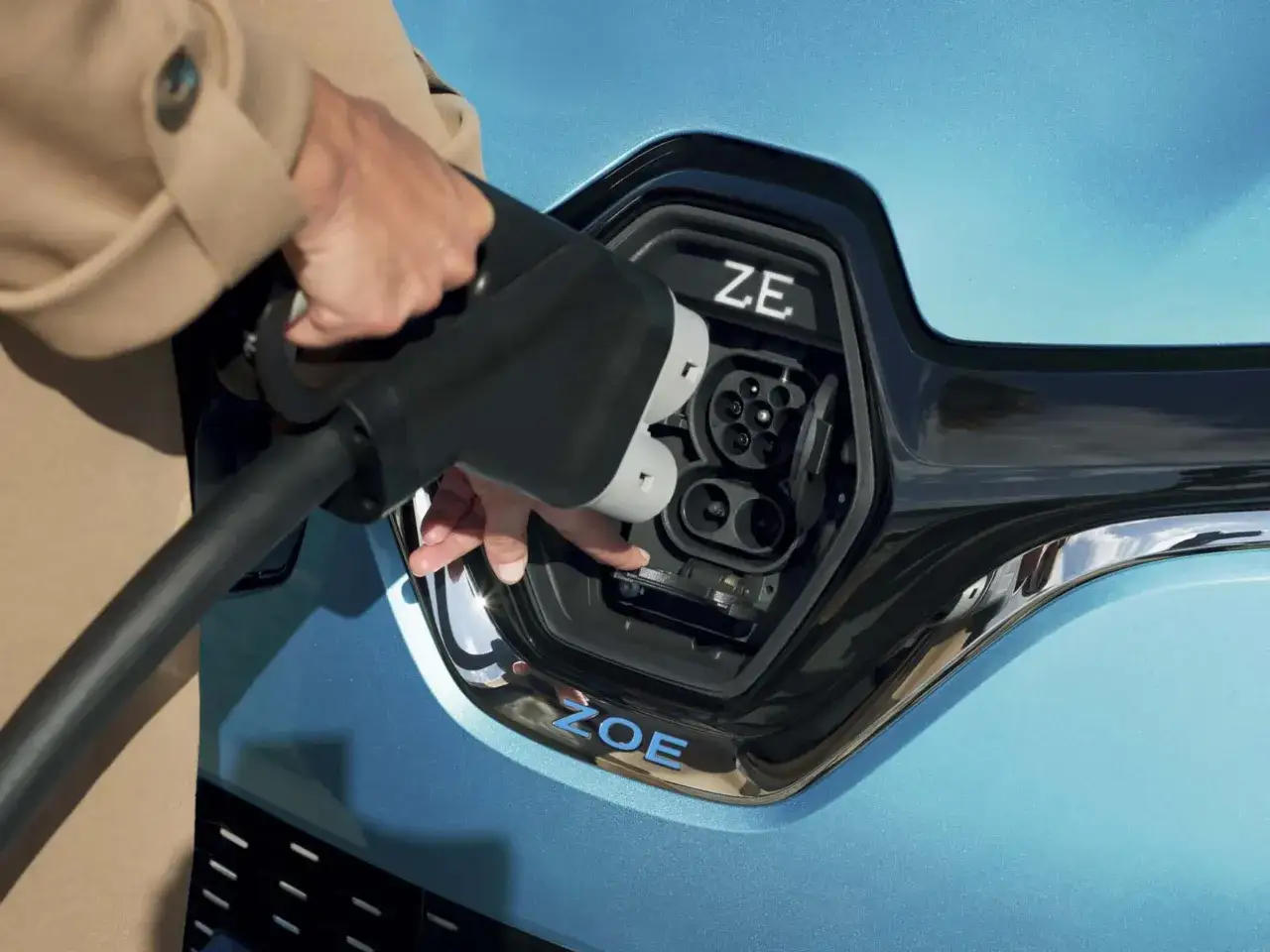 Une main ins&egrave;re le chargeur dans une Renault Zo&eacute;. Le temps de recharge zoe 22kw est rapide.