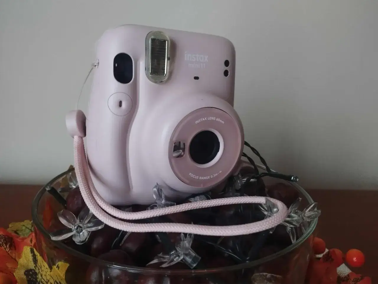 Różowy aparat Instax Mini 11, idealny do robienia zdjęć. W zestawie smycz i ozdobne światełka.