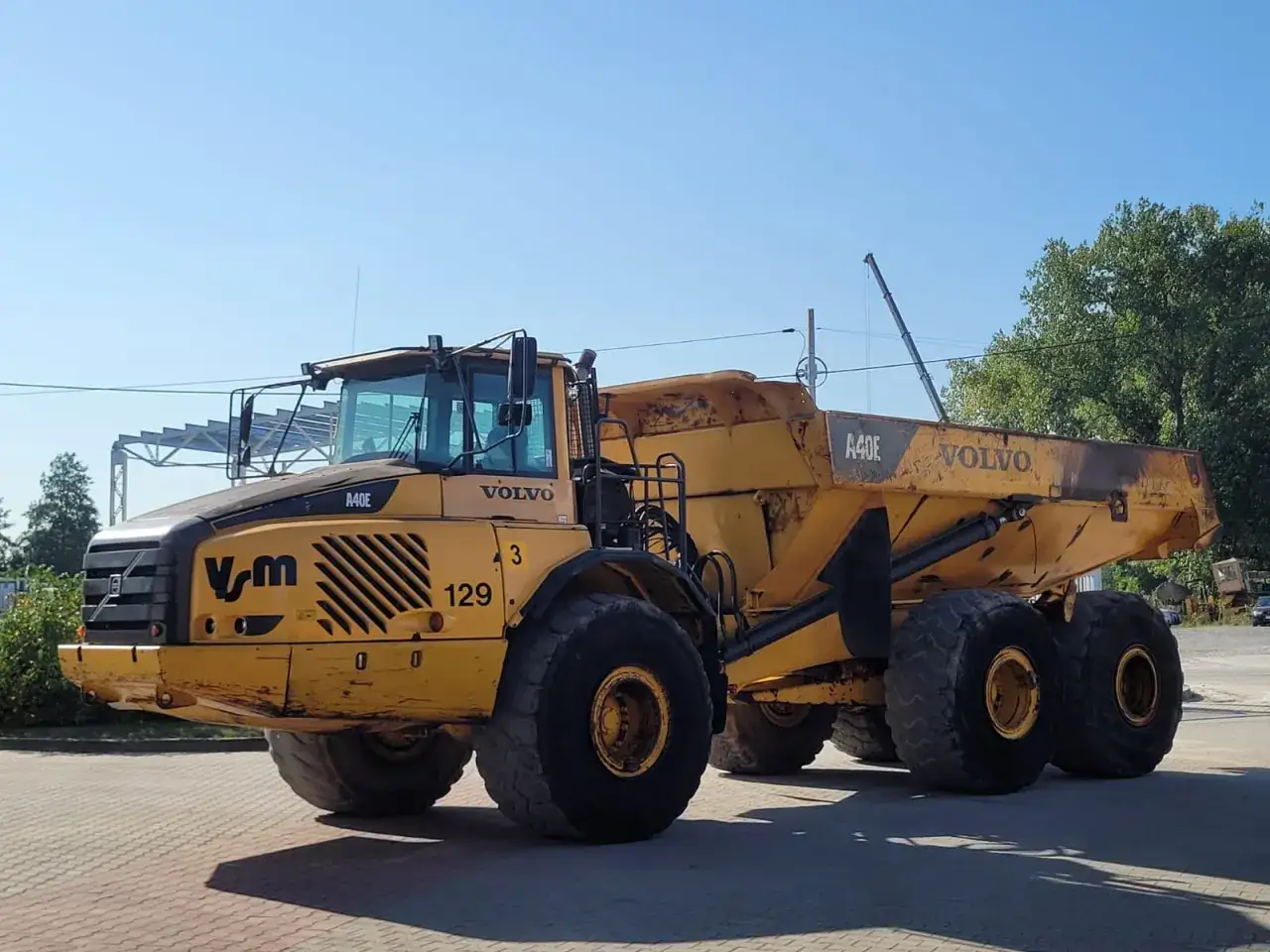 Żółte wozidło budowlane Volvo A40E z numerem 129 gotowe do pracy na placu budowy.
