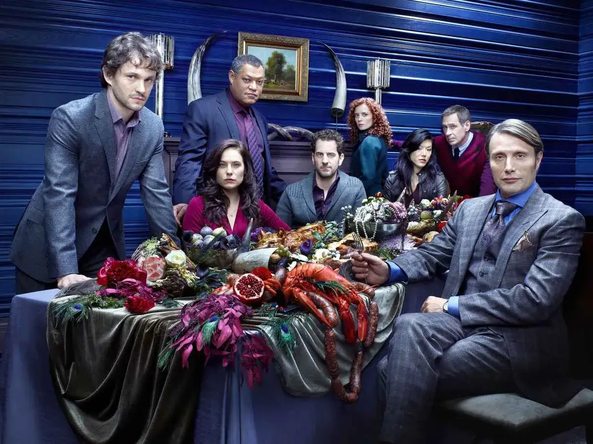 Hannibal obsada przy stole pełnym wykwintnych potraw. Will Graham, Jack Crawford, Alana Bloom, Freddie Lounds, Beverly Katz, Miriam Lass i Hannibal Lecter.