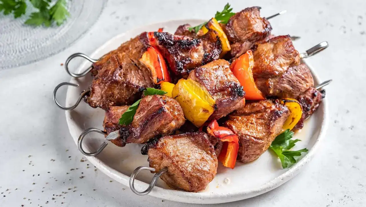 Brochettes de côte de porc grillée, colorées avec des poivrons rouges et jaunes, garnies de persil frais.