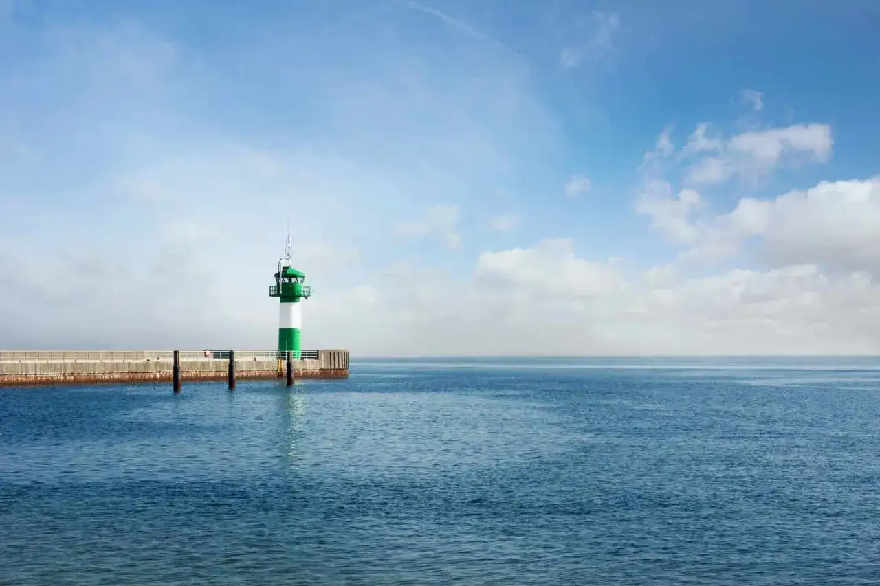 Leuchtturm mit gr&uuml;n-wei&szlig;en Streifen auf einem Pier, ein klassischer fotospot in Schleswig-Holstein.