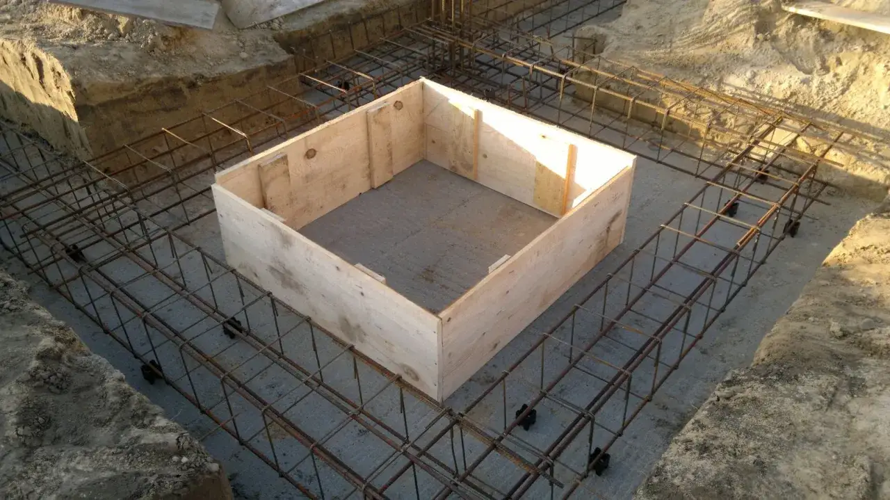 Drewniana forma i zbrojenie na placu budowy. Przygotowania do tego, jak zrobić beton, są widoczne.