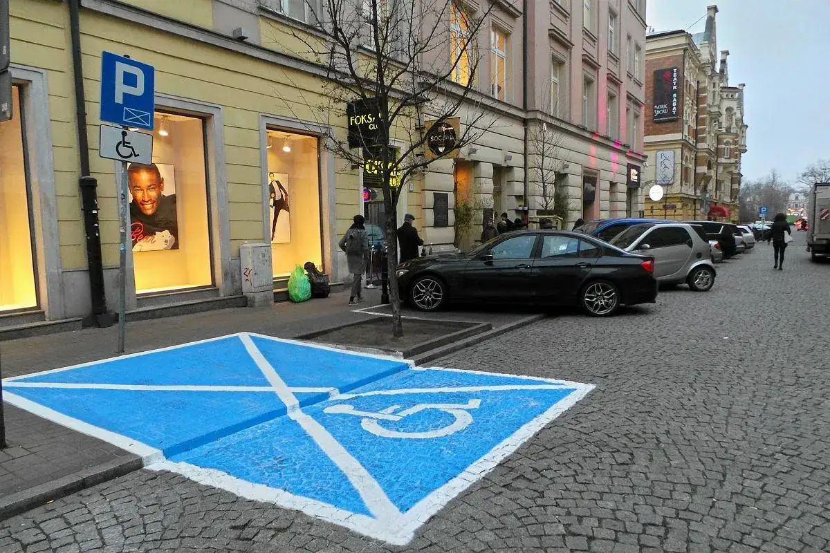 Niebieskie pole z białym symbolem wózka inwalidzkiego to indywidualne miejsce parkingowe dla osoby niepełnosprawnej.