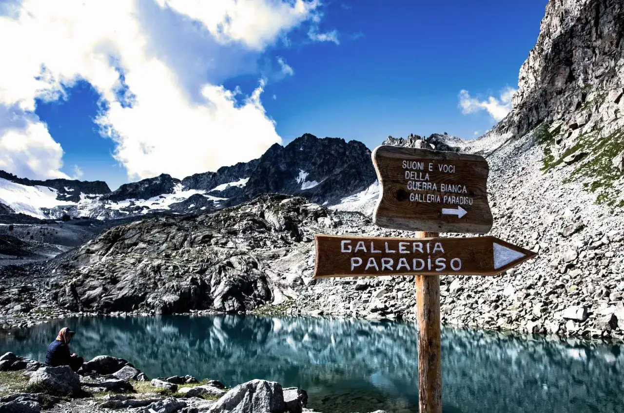Lago alpino con montagne innevate. Cartelli indicano
