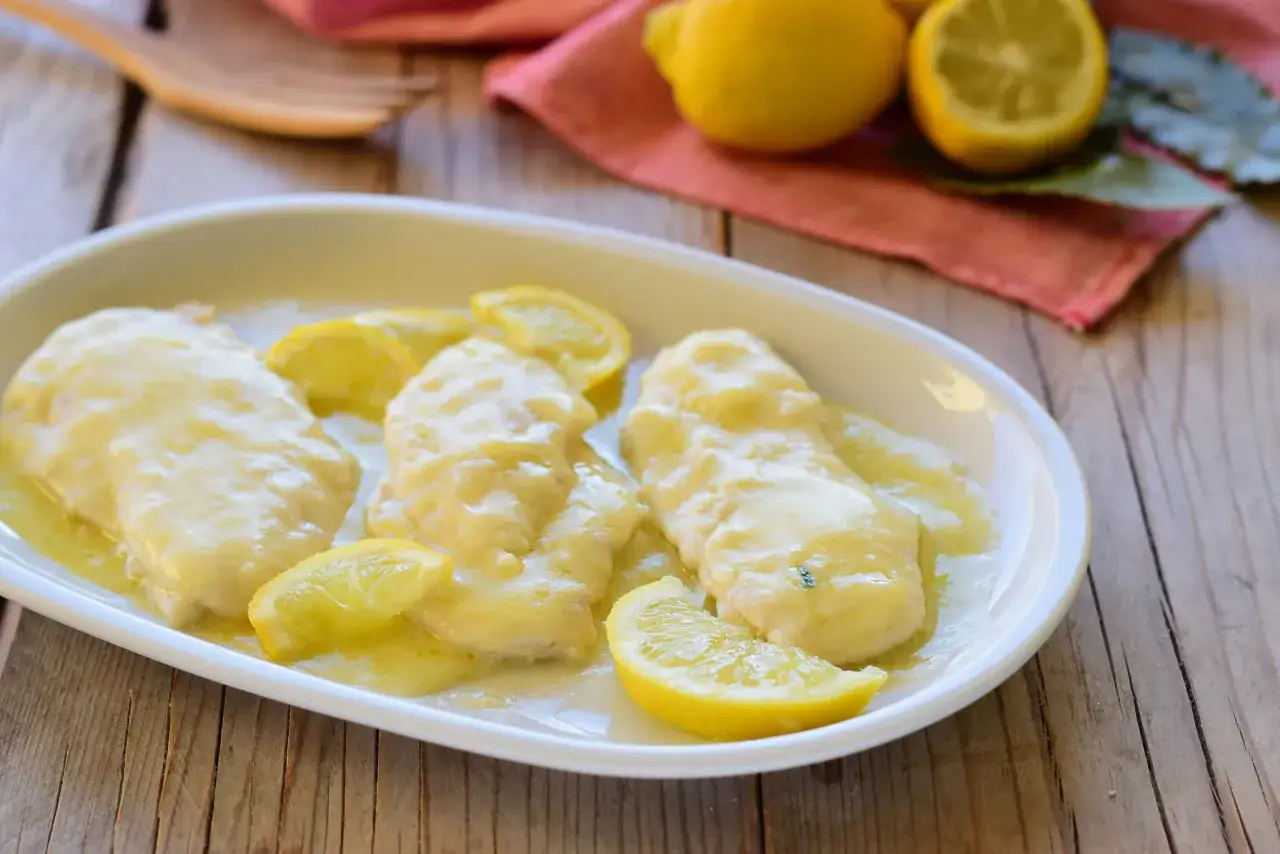 Scaloppine al limone cremose, un piatto invitante con fette di limone fresco su un letto di salsa dorata.