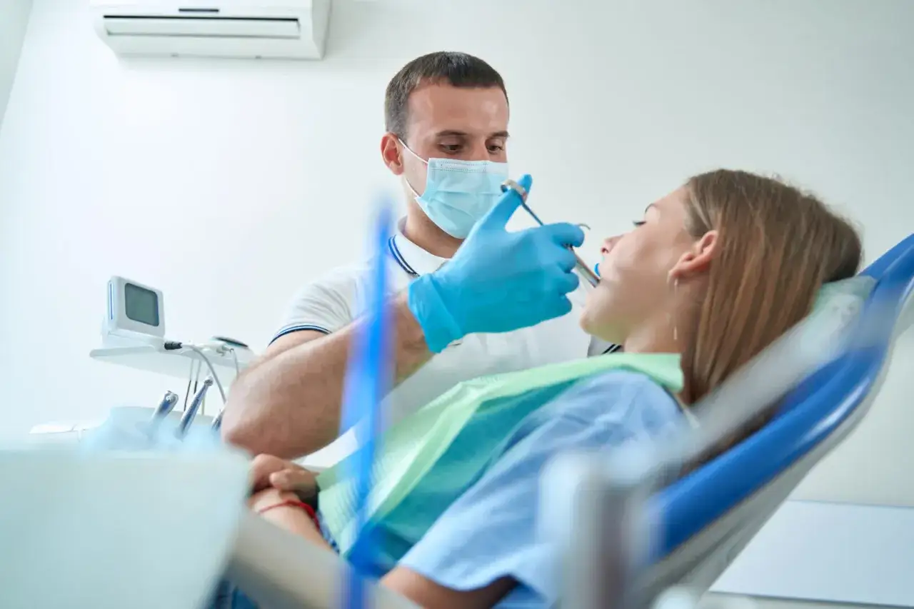 Dentysta podaje znieczulenie miejscowe pacjentce w fotelu stomatologicznym.