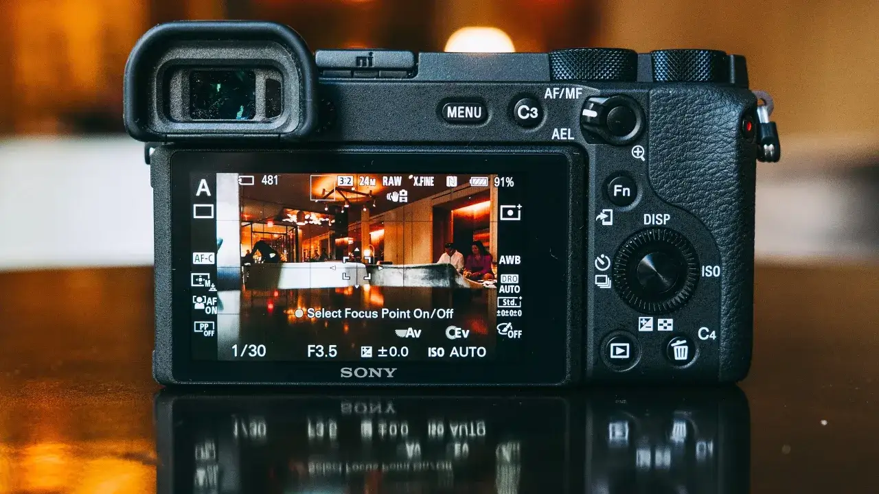 La pantalla de la cámara **Sony a6600** muestra una escena interior con personas. Se aprecian ajustes de exposición y enfoque.
