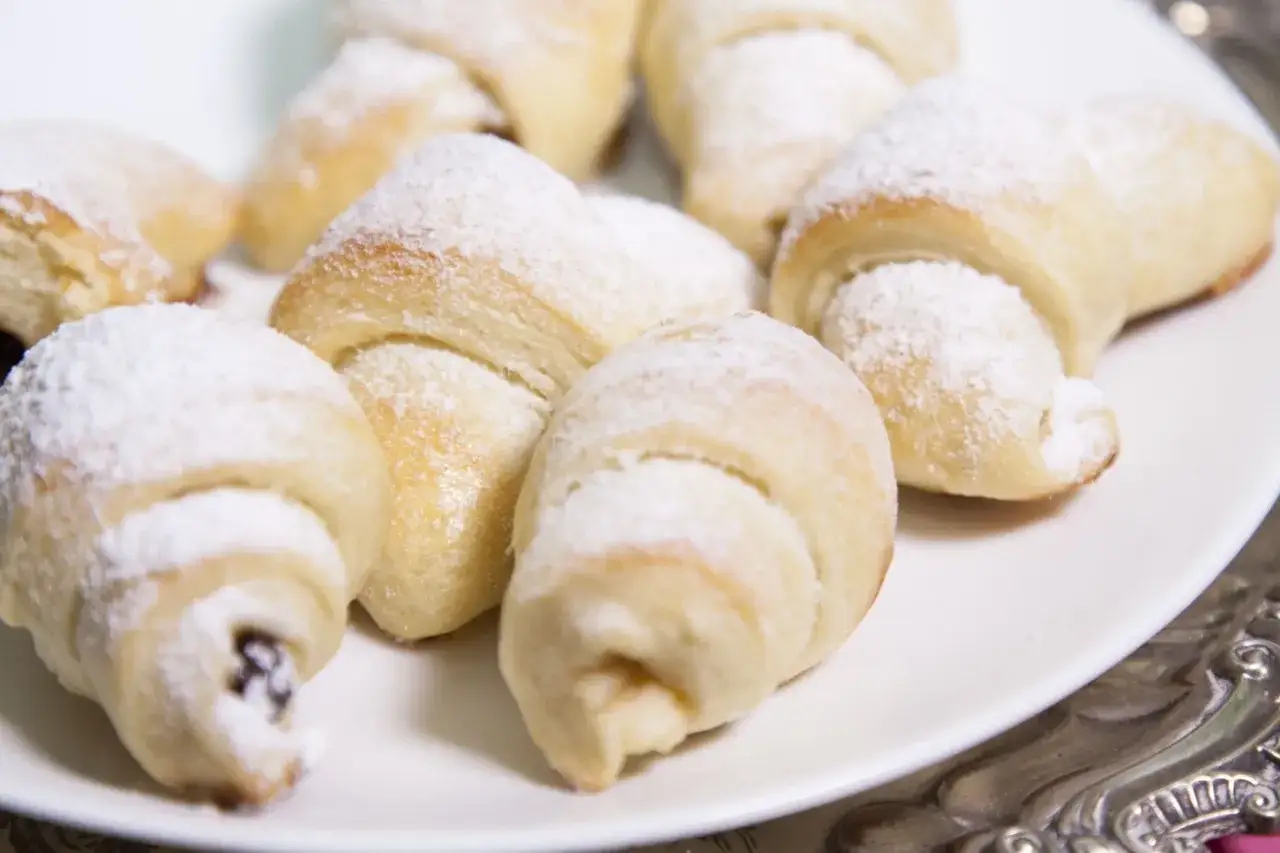 Pyszne, delikatne ciasto topione, posypane cukrem pudrem, ułożone na białym talerzu.