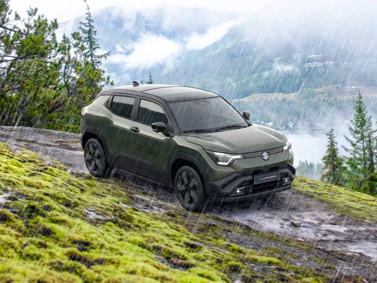 Gr&ouml;n Suzuki Vitara med automatisk v&auml;xell&aring;da k&ouml;r p&aring; en mossig, stenig sluttning i regn.