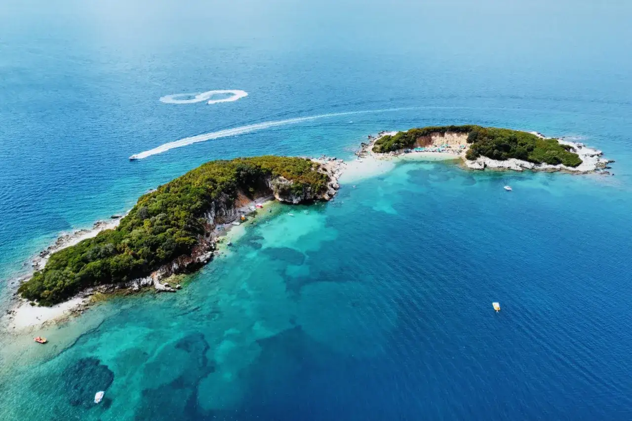 Malownicze albania plaże z turkusową wodą, zielonymi wyspami i łodziami. Idealne miejsce na wakacje.