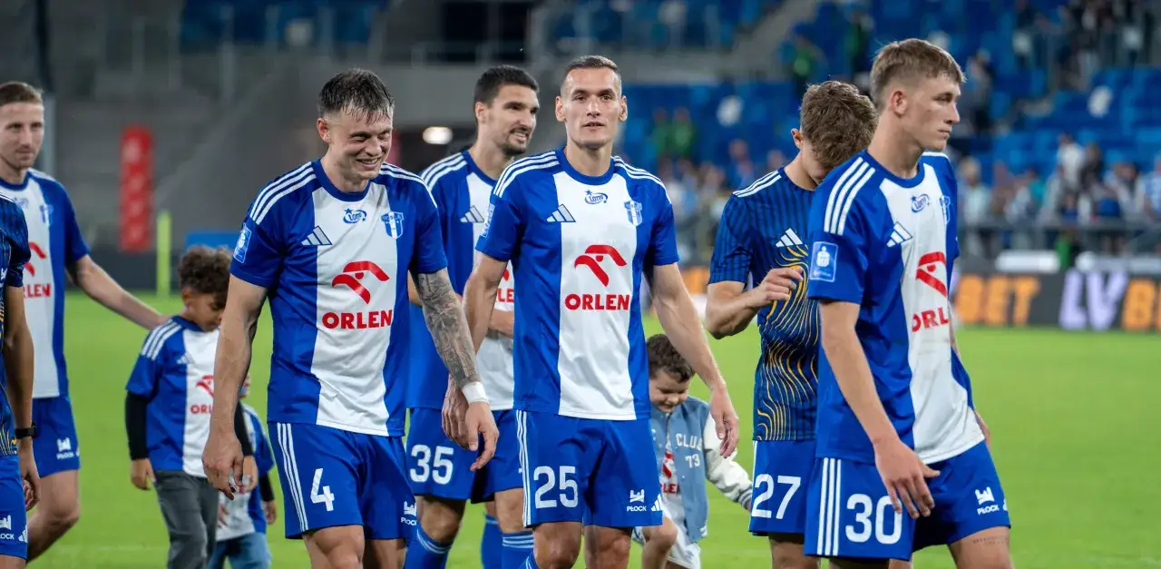 Wisła Płock zawodnicy w niebiesko-białych strojach wychodzą na murawę. Wśr&oacute;d nich widać młodego chłopca.