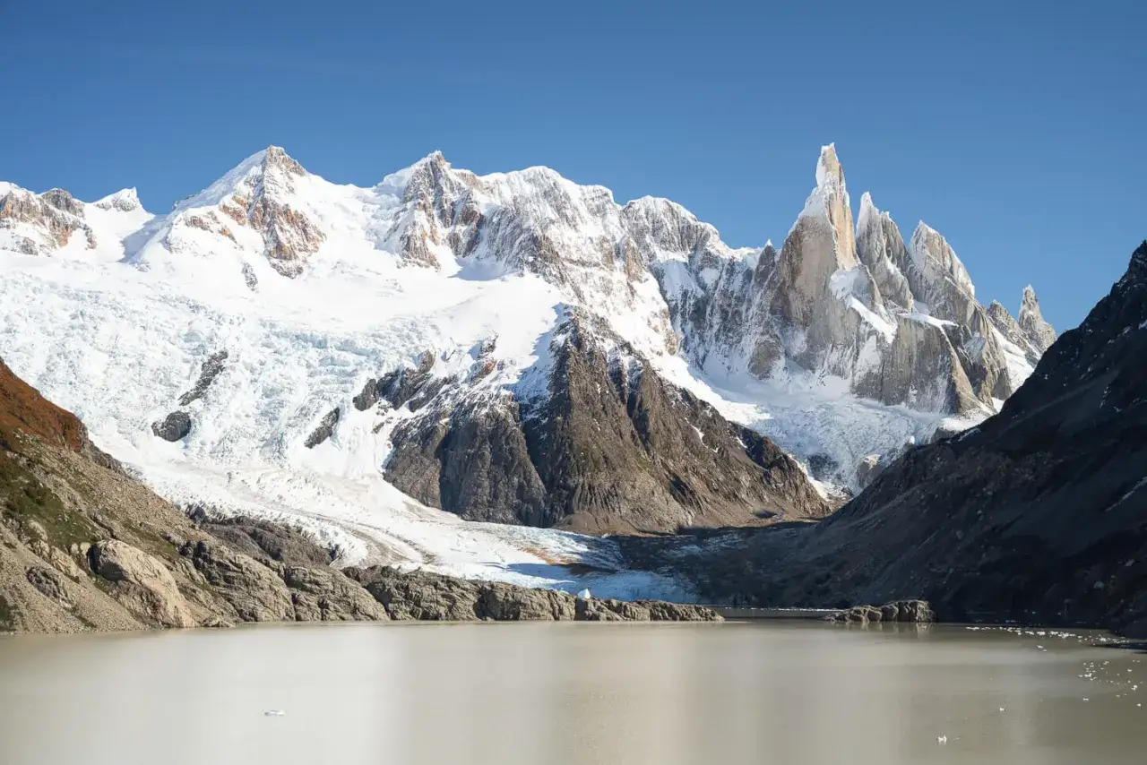 Majest&auml;tische schneebedeckte Gipfel der Torres del Paine ragen &uuml;ber einen Gletscher und einen ruhigen See auf.