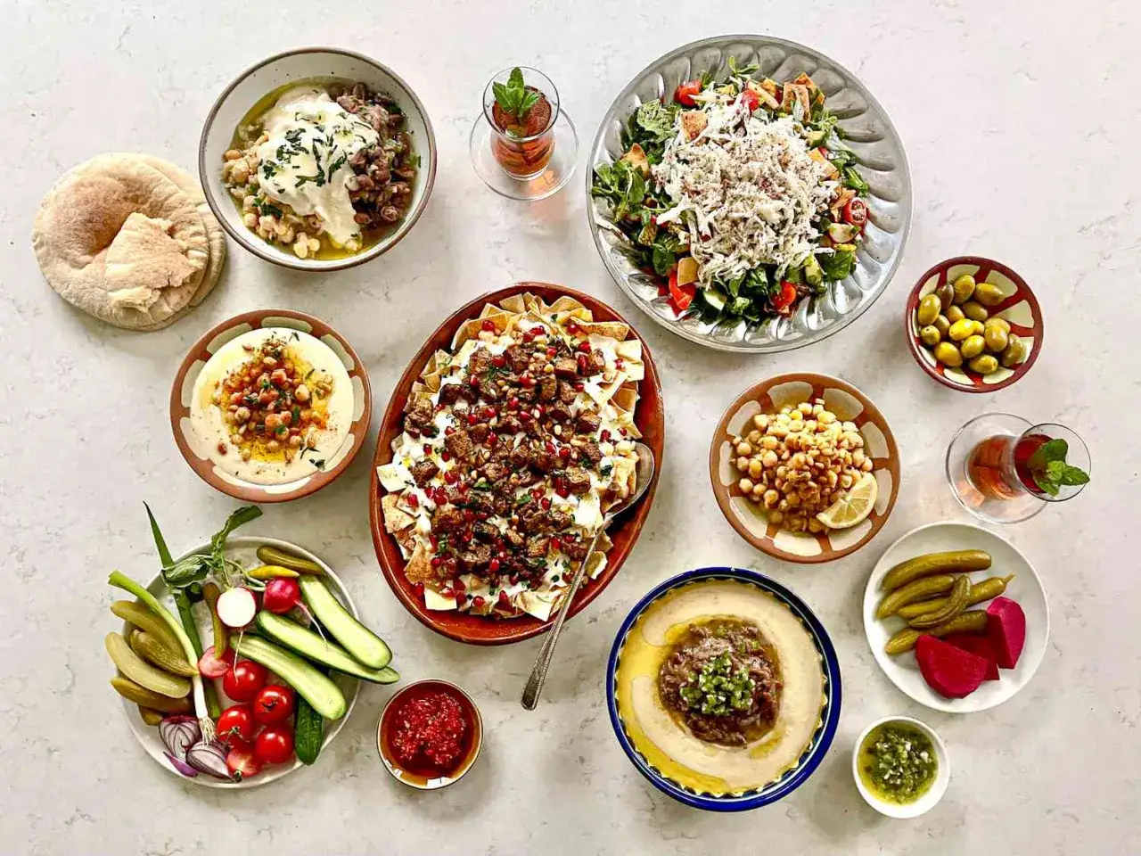 Vielfalt an Gerichten mit Hummus: cremiger Hummus, Kichererbsen, Salat, Fleisch und frisches Gemüse laden zum Genießen ein.