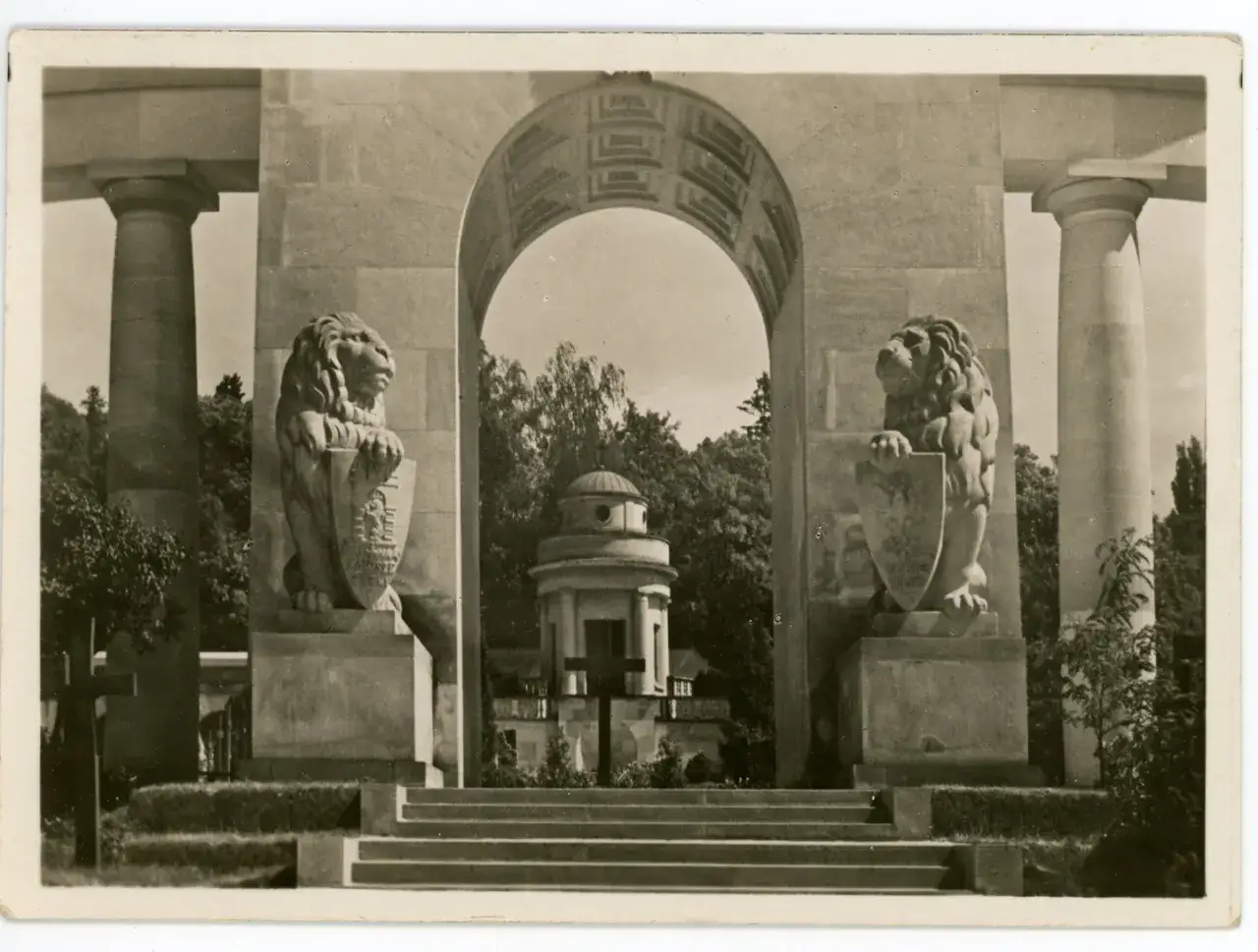 Pomnik Orląt Lwowskich z lwami strzegącymi tarcz. Monumentalny łuk i kolumny.