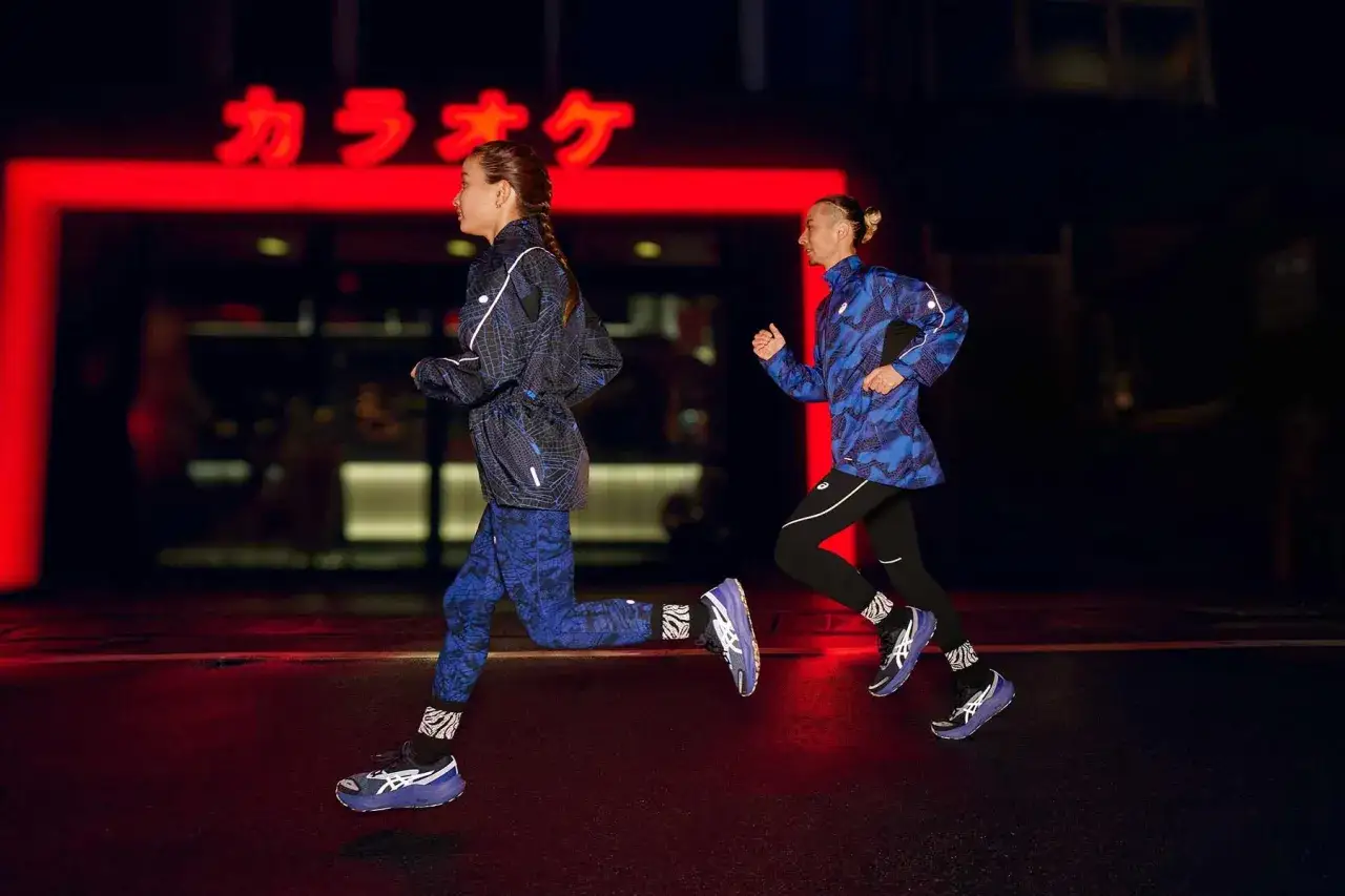 Due runner in abbigliamento tecnico blu con fantasie geometriche corrono di notte. Perfetto per sapere come vestirsi per correre in inverno.