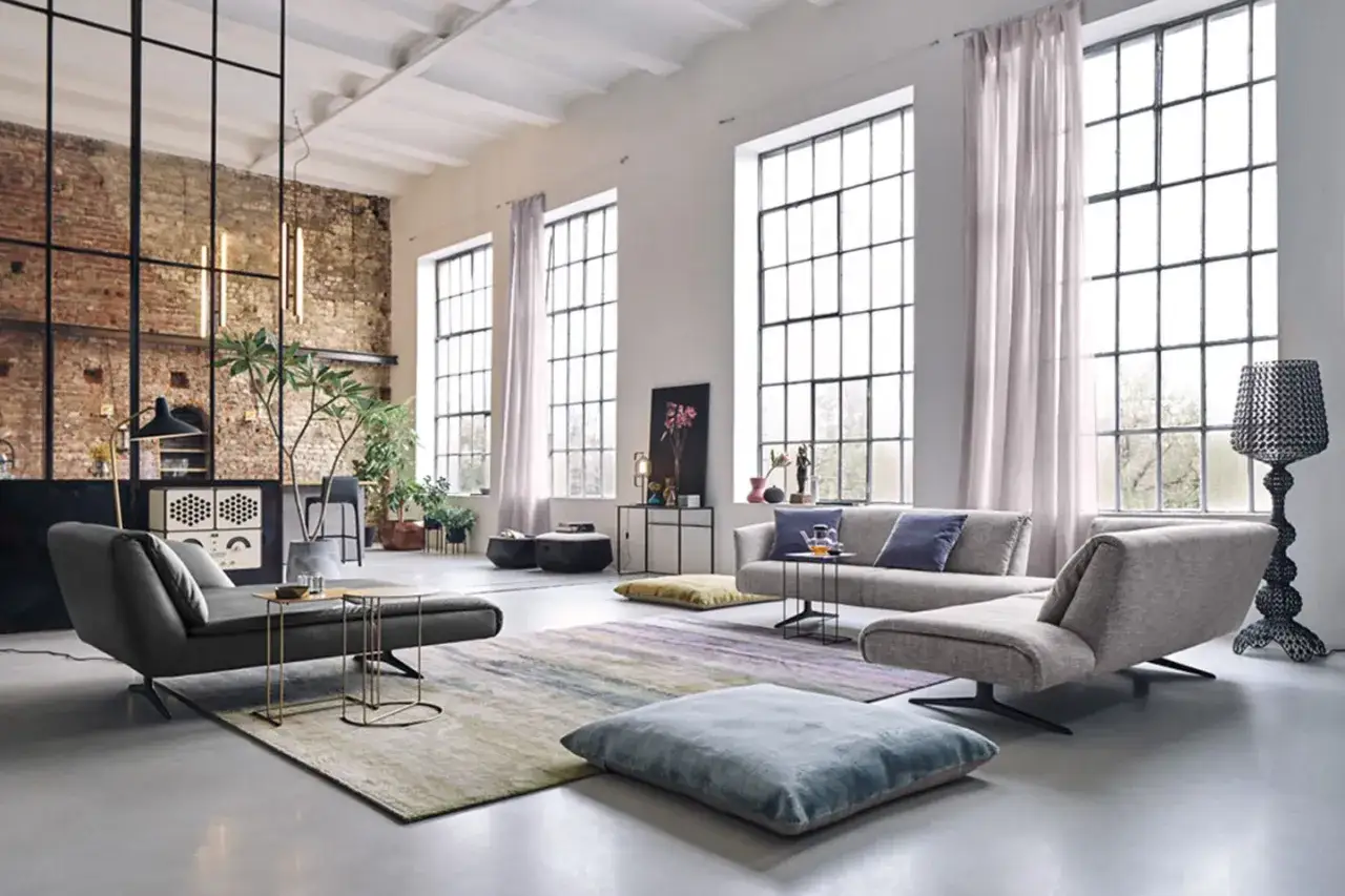 Modernes Loft mit industriellem Charme: Ein stilvolles wohn und schlafzimmer in einem raum, mit großen Fenstern, Ziegelwand und bequemen Möbeln.
