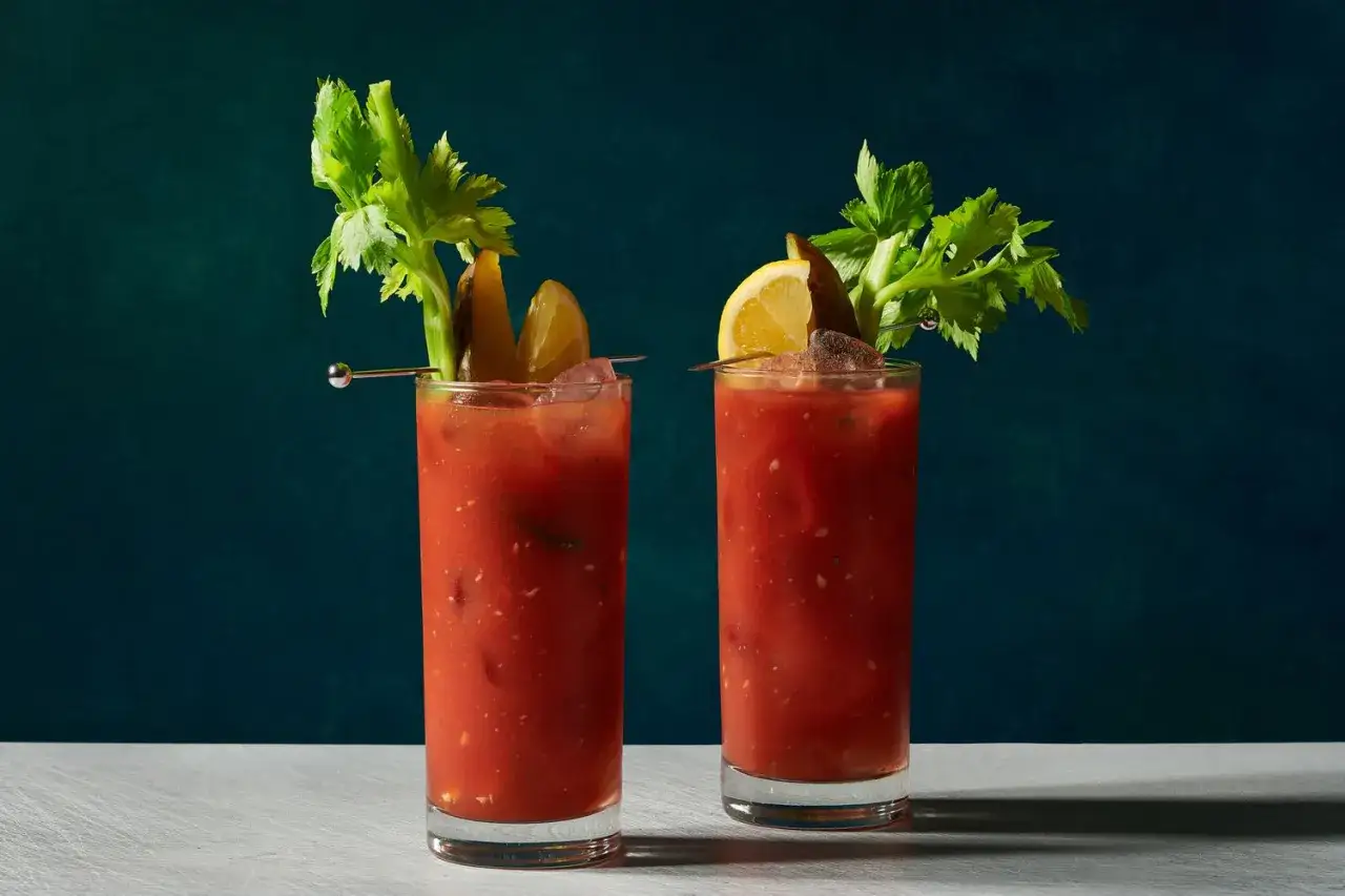 Två glas med en röd, kryddig bloody mary, garnerade med selleri, gurka och citron. Perfekt för en brunch!