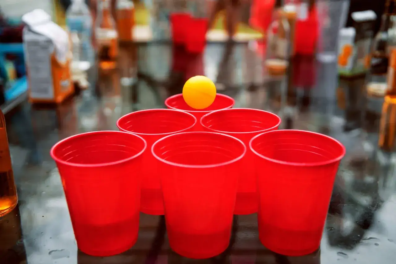 Una pir&aacute;mide de vasos rojos y una pelota amarilla, lista para divertidos juegos para fiestas adultos.