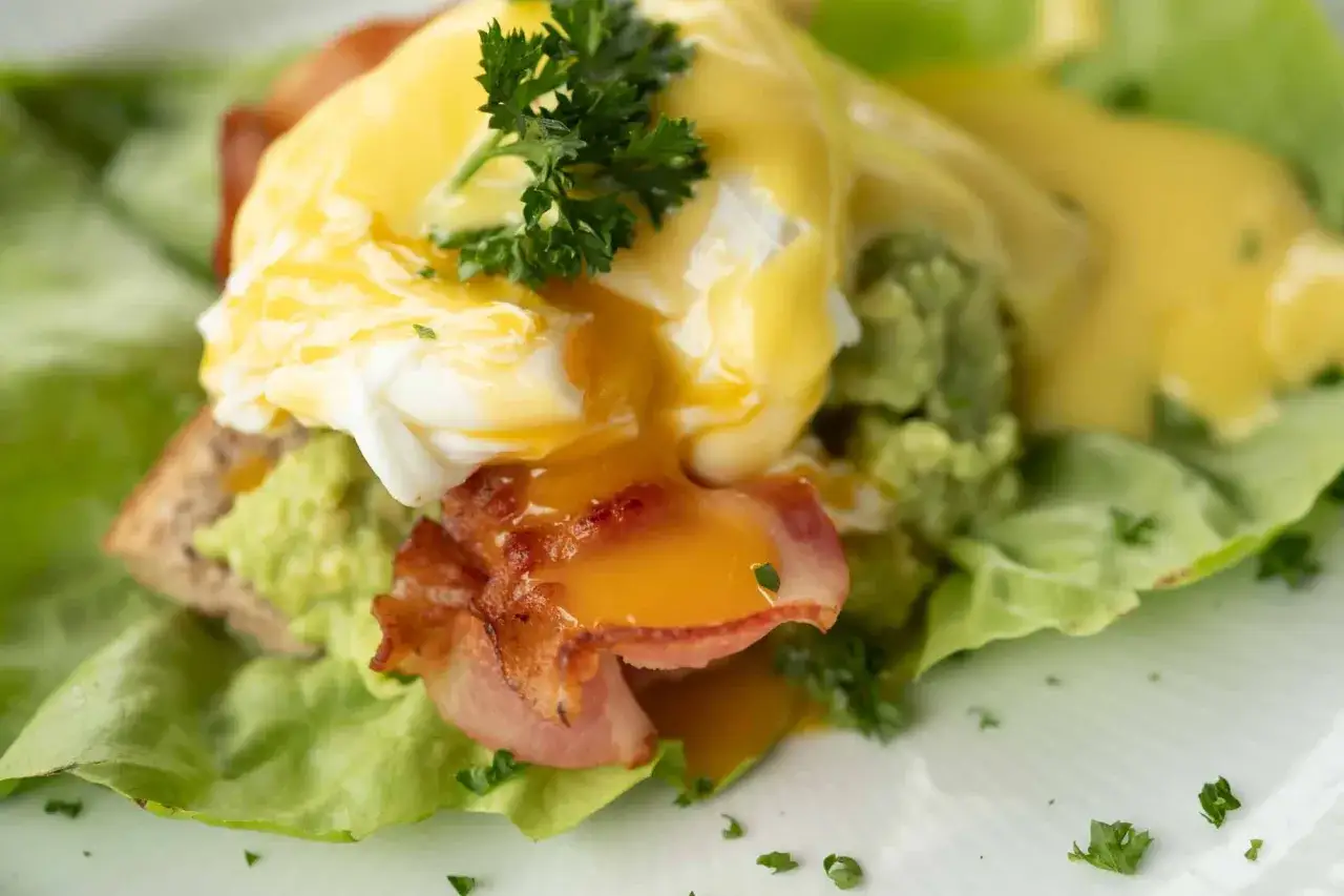 Huevos escalfados con aguacate, tocino y holandesa. Ideal para saber qué comer para romper el ayuno intermitente 16/8.