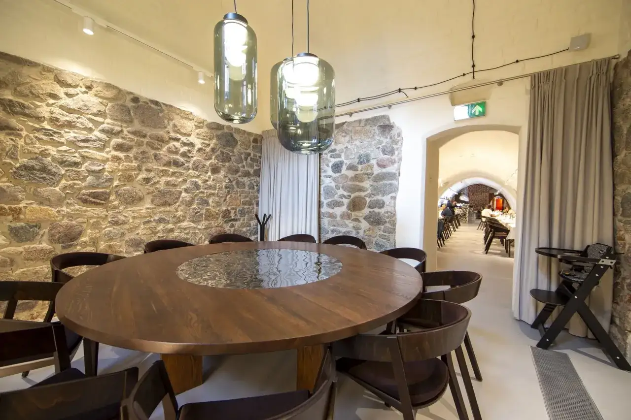 Kameralna sala z kamiennymi ścianami i okrągłym stołem, idealna na spotkanie w najstarszej restauracji w Polsce.