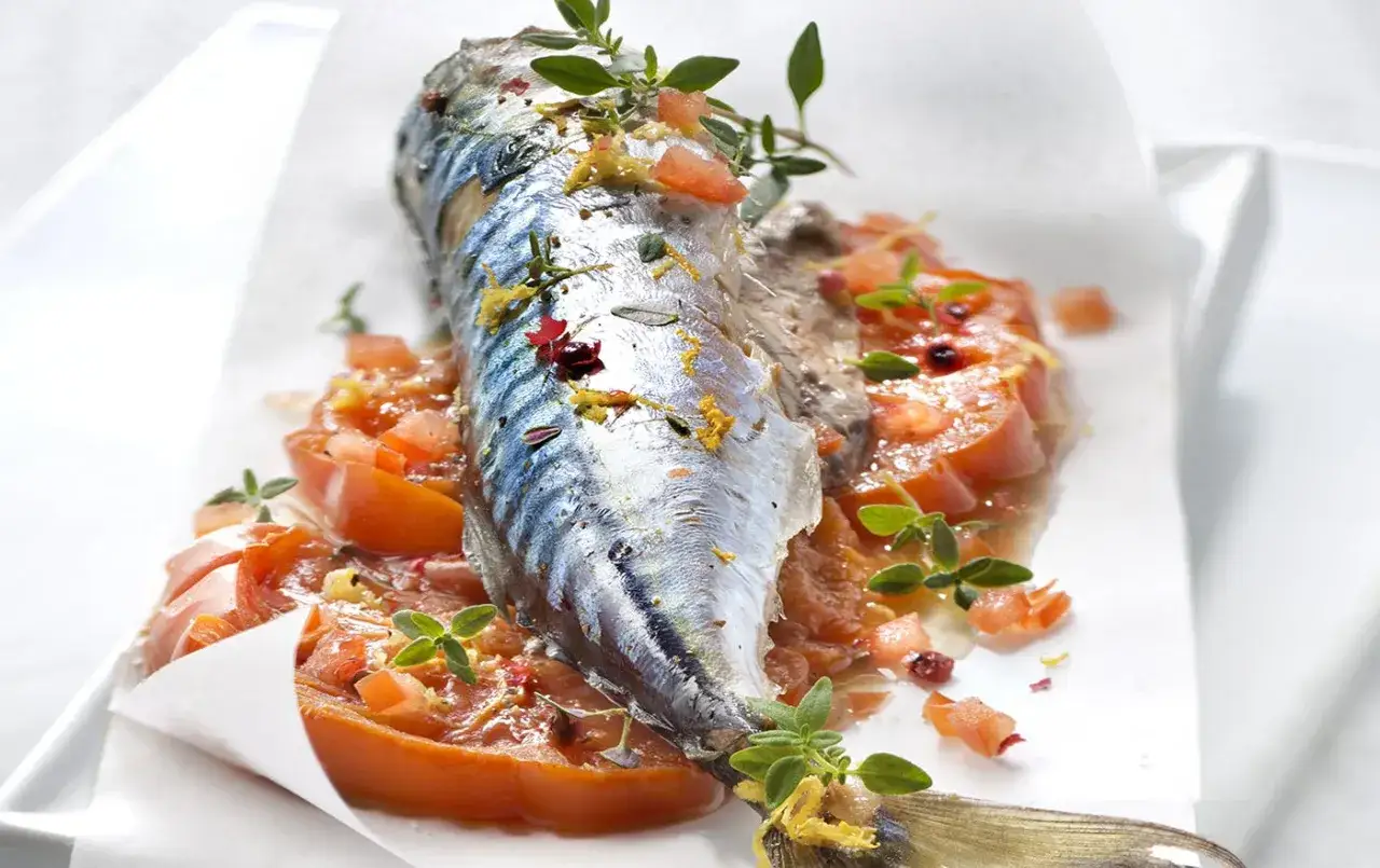 Maquereau entier, cuit en papillote avec des tomates et des herbes fra&icirc;ches, pr&ecirc;t pour un barbecue savoureux.