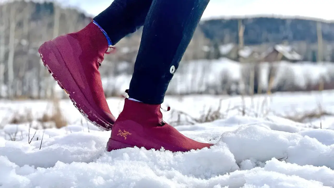 Rote **Schnee Laufschuhe** mit goldenem Logo im tiefen Schnee.