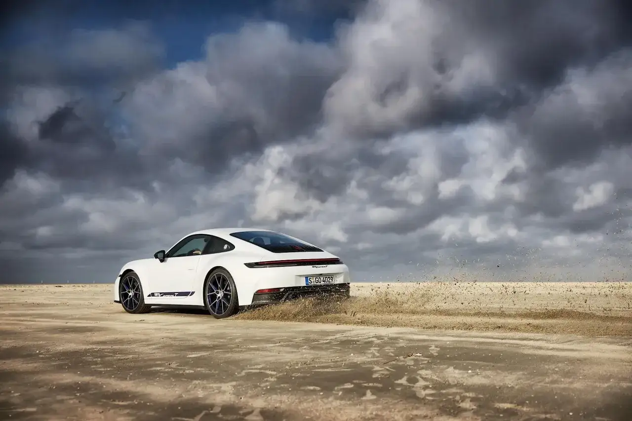 Wei&szlig;er Porsche 911 Carrera T auf sandigem Untergrund, der Staub aufwirbelt. Ein Blick auf die Wertentwicklung dieses Sportwagens.