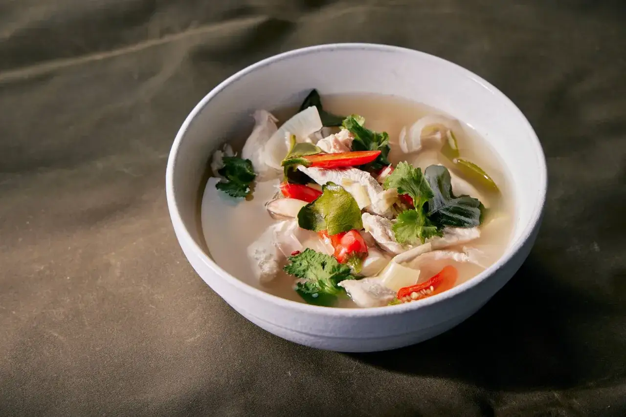 Aromaticzne tom yum z kurczakiem, pełne świeżych ziół, chili i kawałków kurczaka w bulionie.