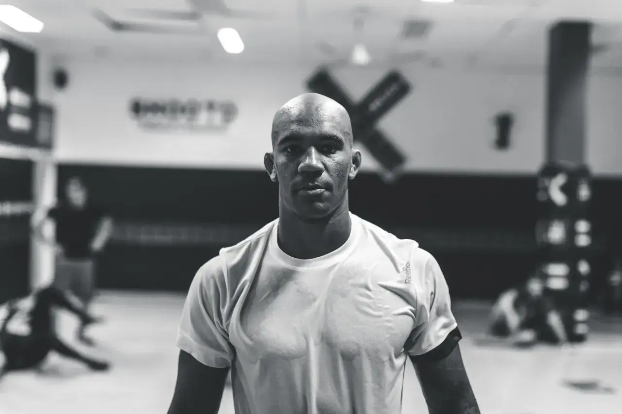 Nico Musoke, en fokuserad MMA-fighter, svettig efter tr&auml;ning i gymmets svarta och vita milj&ouml;.