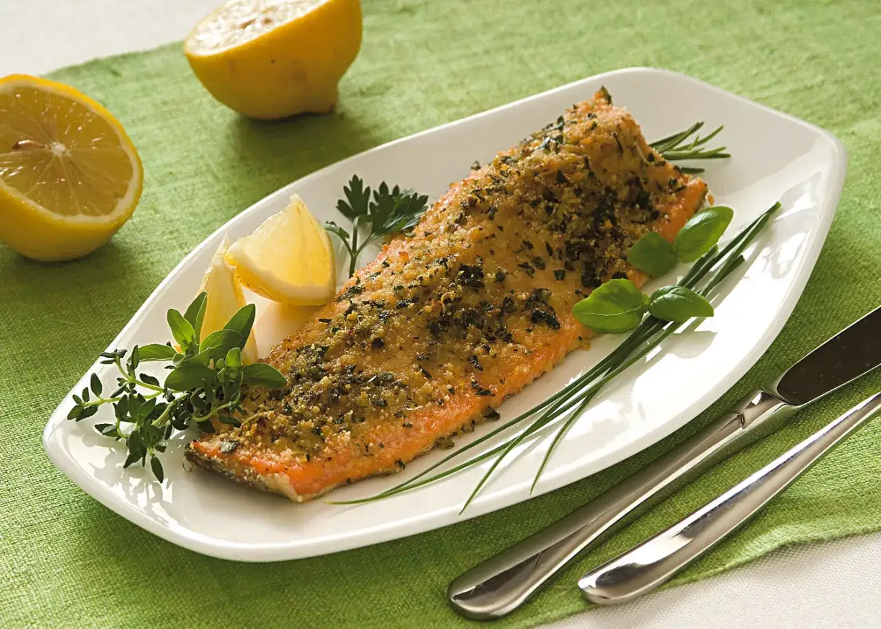 Trota salmonata al forno, croccante e profumata, servita con limone fresco e erbe aromatiche.