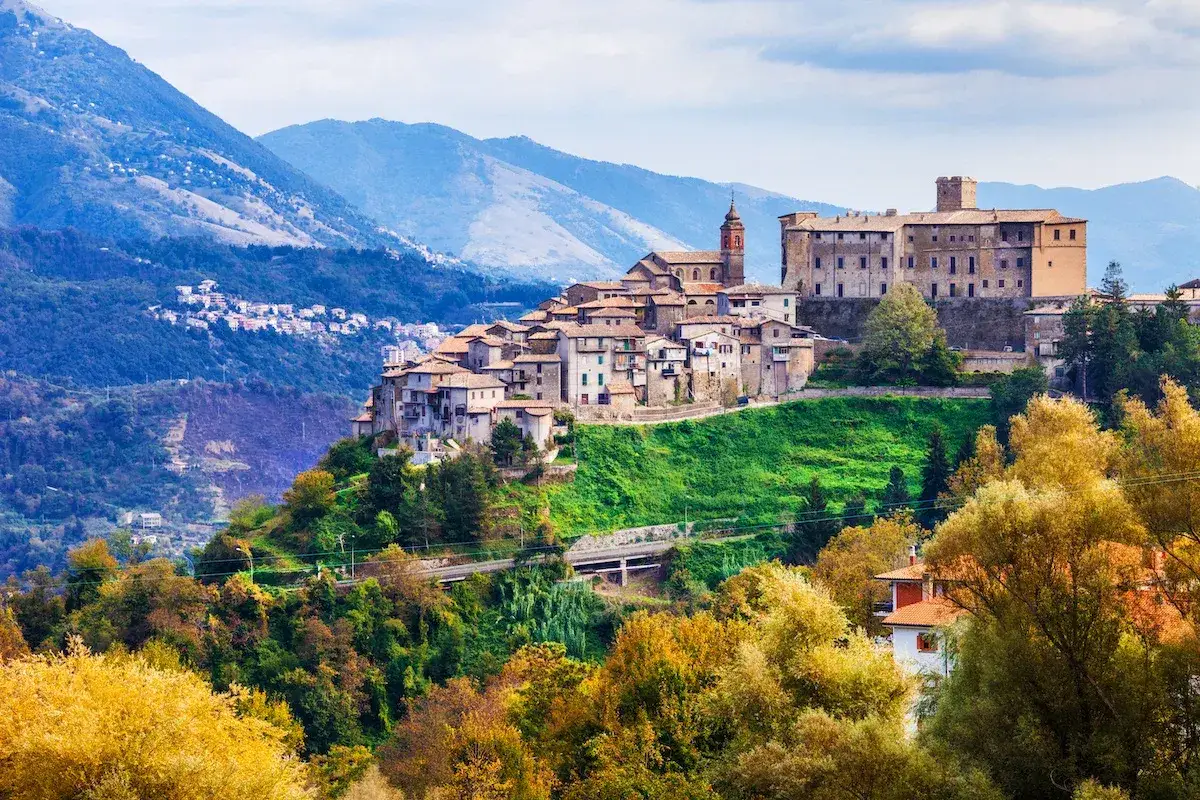 Borgo medievale su una collina verde, con montagne sullo sfondo, un luogo incantevole vicino Roma.